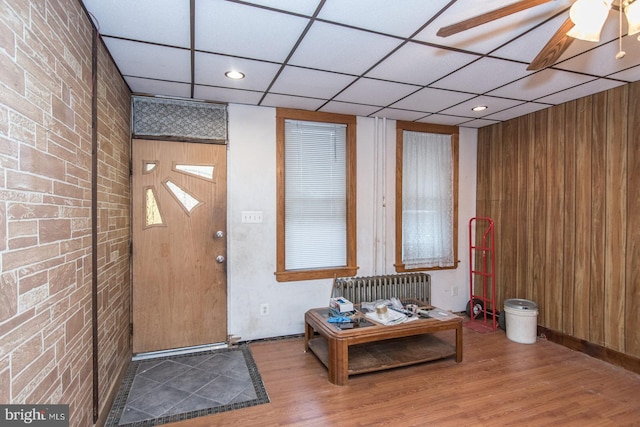 interior space with a paneled ceiling, hardwood / wood-style flooring, radiator, and ceiling fan