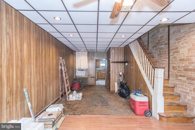 interior space with hardwood / wood-style flooring, ceiling fan, cooling unit, and wood walls