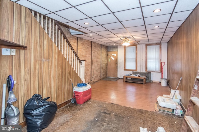 interior space with hardwood / wood-style flooring, a paneled ceiling, and wooden walls