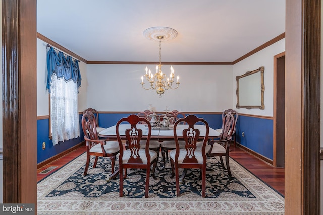 dining space with ornamental molding, hardwood / wood-style flooring, and a notable chandelier