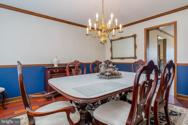 dining space featuring ornamental molding, a notable chandelier, and hardwood / wood-style flooring