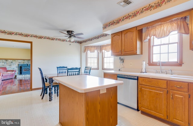 kitchen with a wood stove, ceiling fan, dishwasher, sink, and a kitchen island