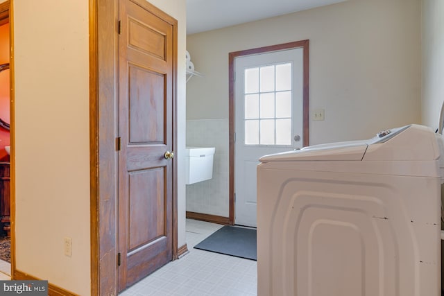 clothes washing area featuring washer / clothes dryer and tile walls