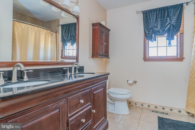 bathroom featuring tile patterned flooring, vanity, a healthy amount of sunlight, and toilet