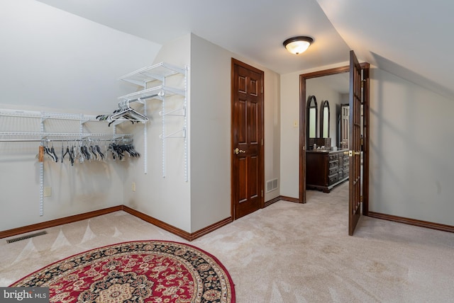 spacious closet with light colored carpet and lofted ceiling