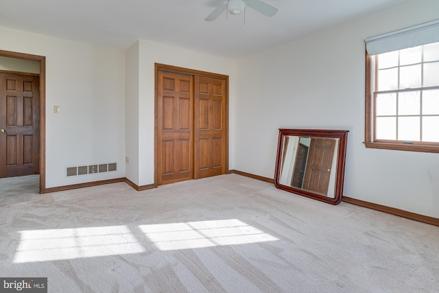 unfurnished bedroom featuring ceiling fan, light colored carpet, and a closet