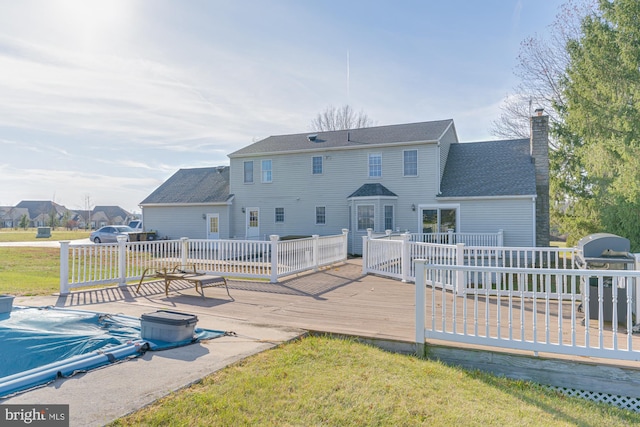 back of property with a deck and a yard