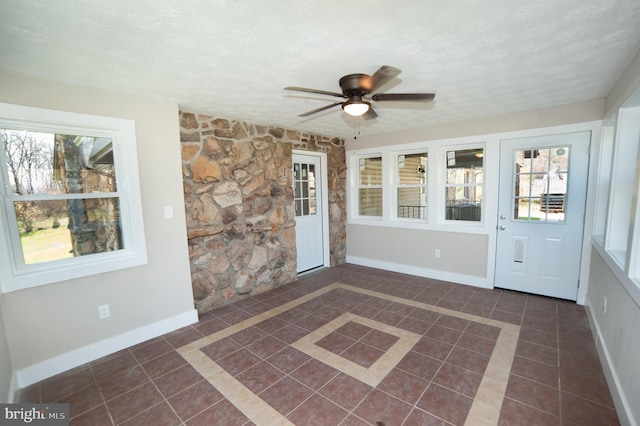 unfurnished sunroom featuring ceiling fan