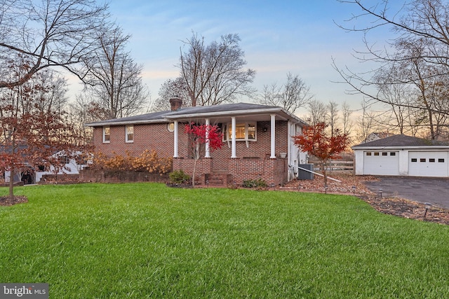 view of front of property with a lawn, an outdoor structure, covered porch, central AC unit, and a garage