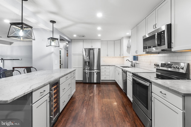 kitchen with appliances with stainless steel finishes, dark wood-type flooring, decorative light fixtures, white cabinetry, and a kitchen island