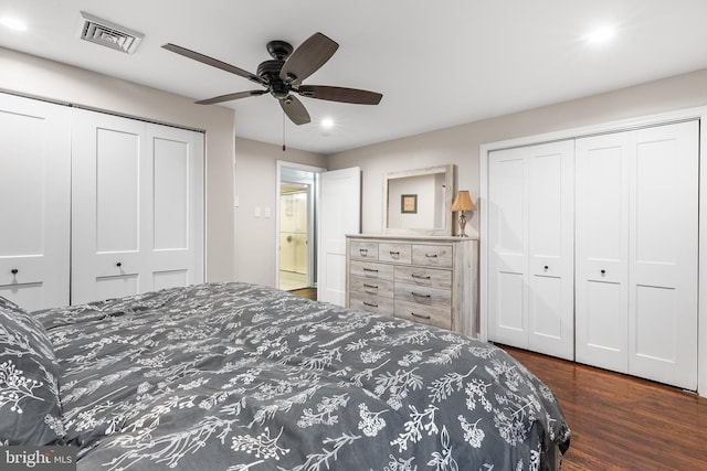 bedroom with ceiling fan, dark hardwood / wood-style flooring, and two closets