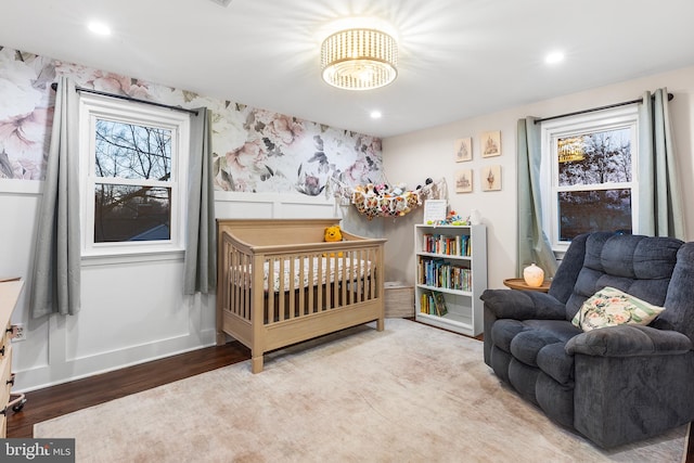 bedroom with a crib and light wood-type flooring