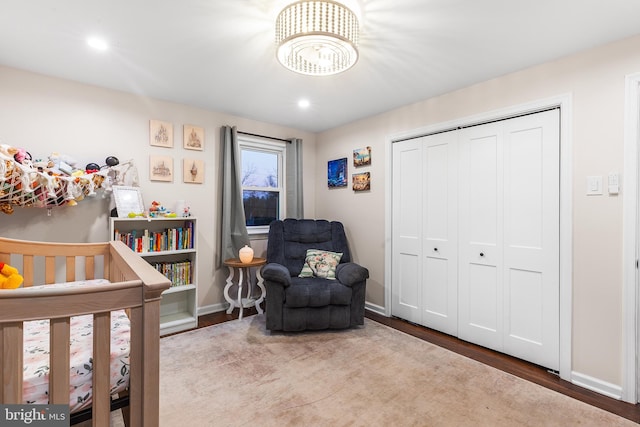 bedroom with hardwood / wood-style floors, a crib, and a closet