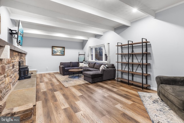 living room featuring a wood stove, crown molding, beamed ceiling, and wood-type flooring