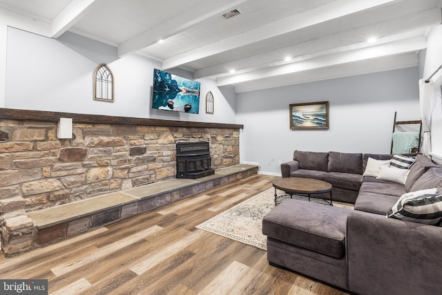 living room featuring beam ceiling, hardwood / wood-style flooring, and a wood stove