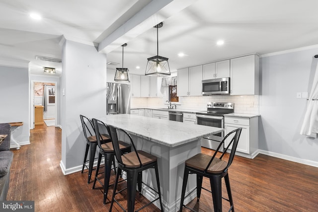 kitchen featuring stainless steel appliances, crown molding, dark wood-type flooring, white cabinets, and hanging light fixtures