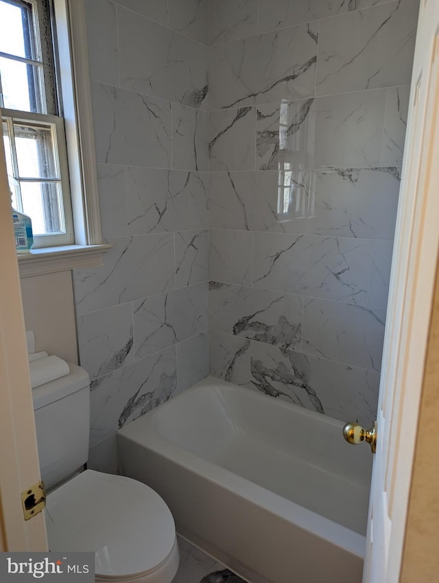 bathroom featuring tiled shower / bath combo and toilet