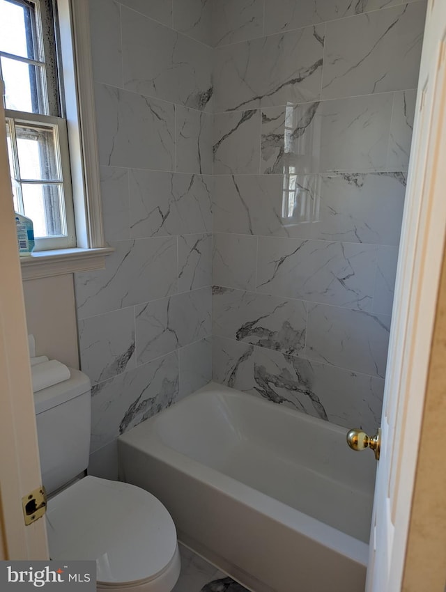 bathroom featuring tiled shower / bath combo and toilet