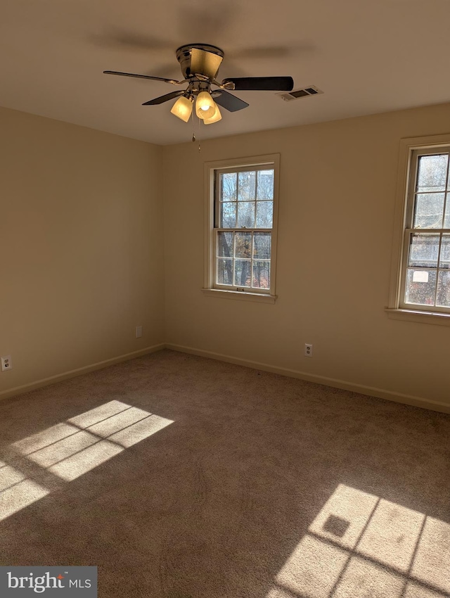 spare room featuring carpet flooring, a wealth of natural light, and ceiling fan