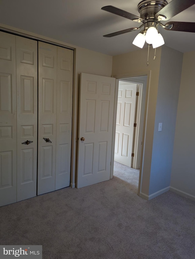 unfurnished bedroom with ceiling fan, light carpet, and a closet