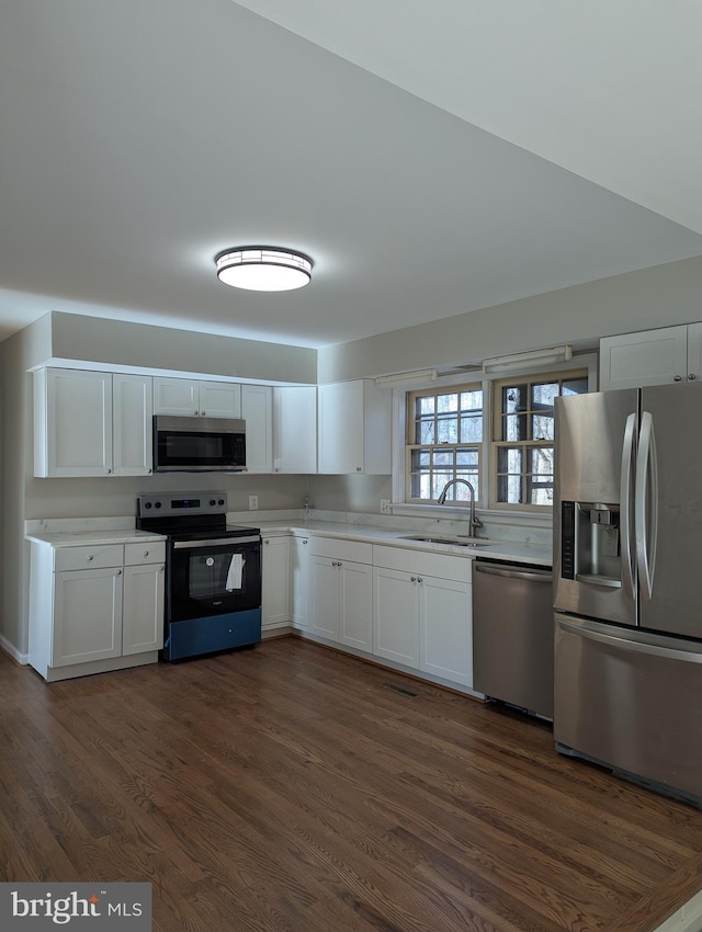 kitchen featuring dark hardwood / wood-style flooring, white cabinetry, sink, and appliances with stainless steel finishes