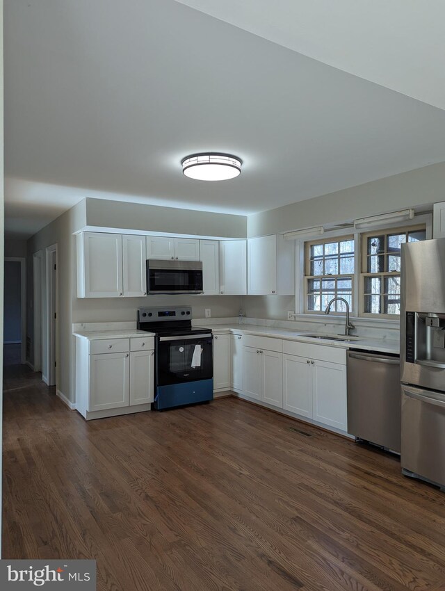 kitchen with white cabinetry, dark hardwood / wood-style flooring, stainless steel appliances, and sink