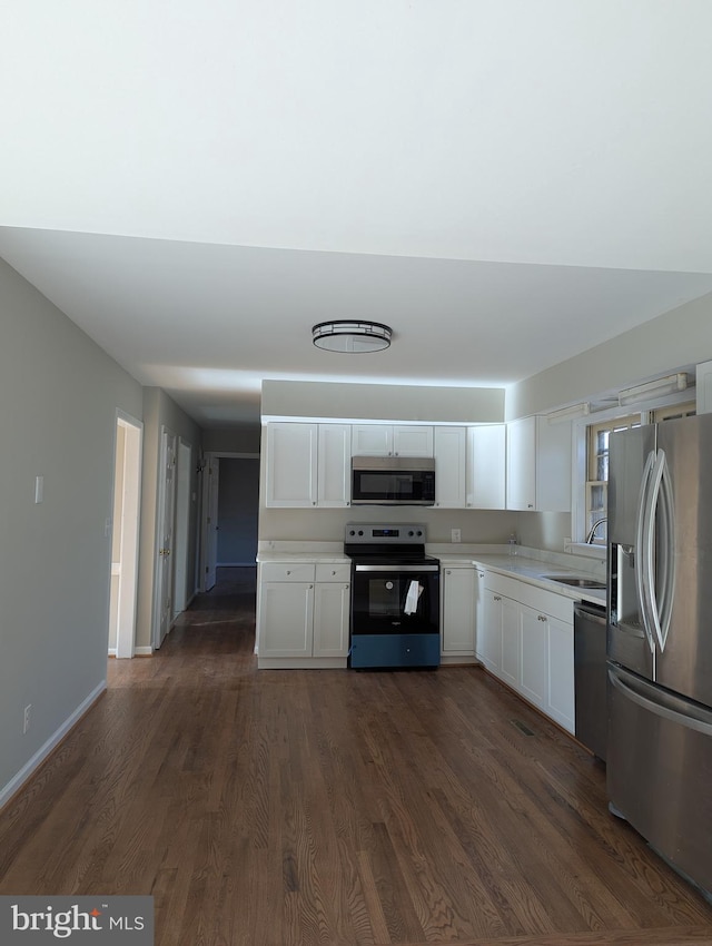 kitchen with dark hardwood / wood-style floors, white cabinetry, sink, and appliances with stainless steel finishes