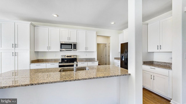 kitchen with white cabinetry, stainless steel appliances, and dark stone counters