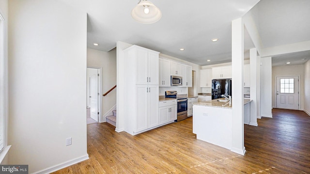 kitchen with a kitchen island with sink, white cabinets, light stone countertops, appliances with stainless steel finishes, and light hardwood / wood-style floors