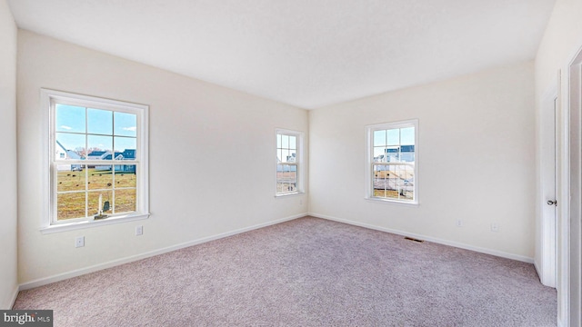 carpeted spare room featuring plenty of natural light