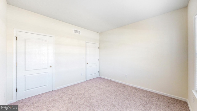 unfurnished bedroom with light carpet and a closet