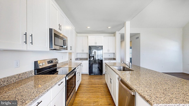 kitchen featuring white cabinetry, sink, a kitchen island with sink, appliances with stainless steel finishes, and light wood-type flooring