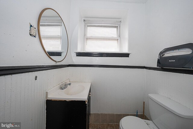 bathroom with tile patterned floors, vanity, wood walls, and toilet