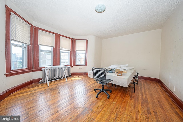 office area featuring wood-type flooring, a textured ceiling, and radiator heating unit