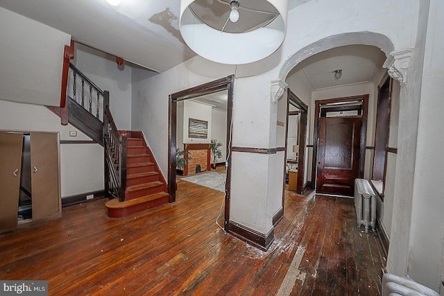 entryway with dark hardwood / wood-style flooring, ornate columns, and radiator