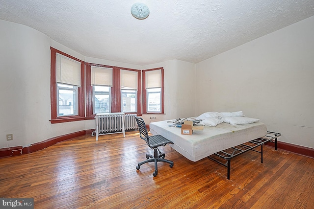 bedroom featuring dark hardwood / wood-style flooring, radiator heating unit, and a textured ceiling