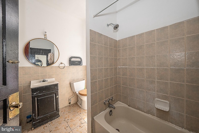 full bathroom with tile patterned flooring, toilet, vanity, tile walls, and tiled shower / bath