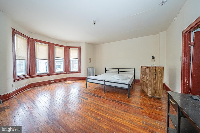 bedroom with radiator heating unit and dark hardwood / wood-style flooring