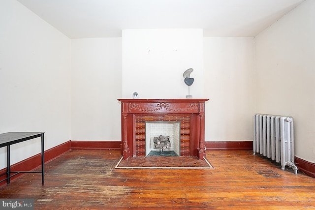 living room featuring dark hardwood / wood-style flooring, radiator, and a tiled fireplace