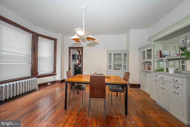 dining area with radiator, a chandelier, and dark hardwood / wood-style floors