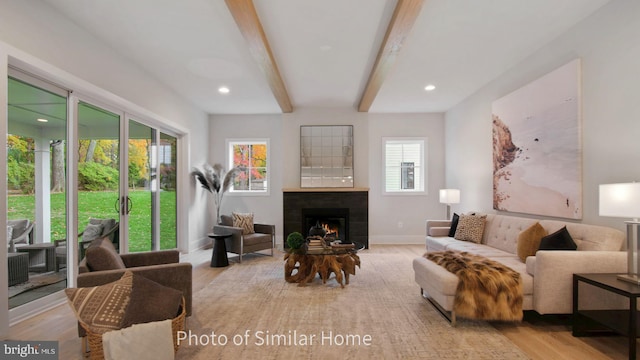 living room featuring light wood-type flooring, a fireplace, and beamed ceiling