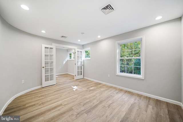 spare room with plenty of natural light, light hardwood / wood-style flooring, and french doors