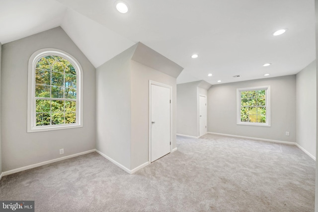 spare room with light colored carpet and vaulted ceiling