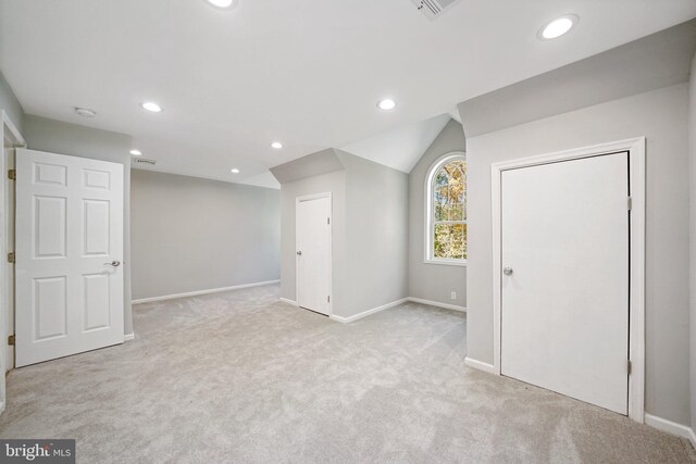 interior space featuring light colored carpet and lofted ceiling