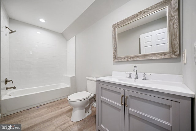 full bathroom with toilet, vanity, wood-type flooring, and tiled shower / bath