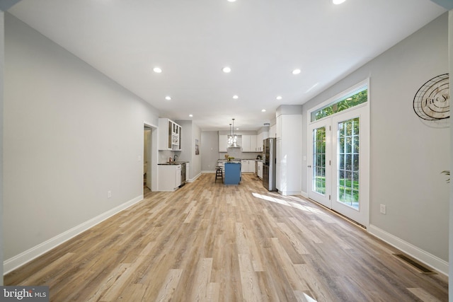 unfurnished living room featuring french doors and light hardwood / wood-style floors