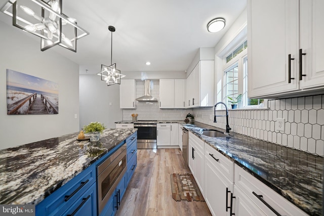 kitchen with white cabinetry, blue cabinets, wall chimney exhaust hood, and sink