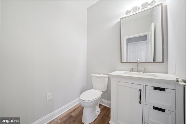 bathroom with wood-type flooring, vanity, and toilet