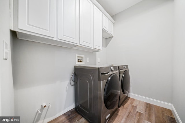 laundry room featuring light hardwood / wood-style floors, cabinets, and washing machine and clothes dryer