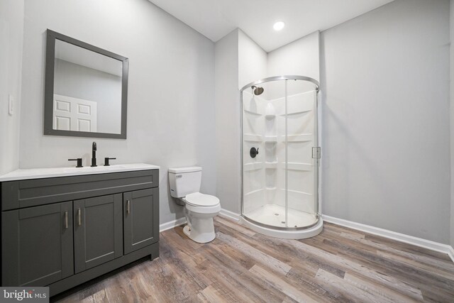 bathroom with a shower with shower door, toilet, wood-type flooring, and vanity